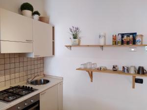 a kitchen with a sink and a stove and shelves at Appartamento Vecchia Domo in Domodossola