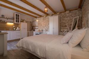 - une chambre avec un grand lit et un mur en pierre dans l'établissement Koko Apartments, à Korčula