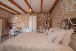 a bedroom with a white bed with a stone wall at Koko Apartments in Korčula