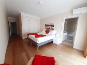 a bedroom with a white bed and a red chair at Vila Porto in Vila Nova de Gaia