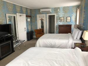 a hotel room with two beds and a television at Seaway Manor B&B in Gananoque