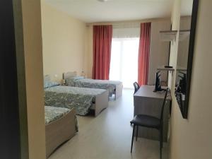 a hotel room with two beds and a desk and a television at Stella Maris Casa per ferie sul mare in Anzio