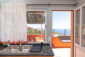 a kitchen with a sink and a view of the ocean at Apartment Laranjeiras in Calheta