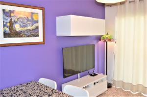 sala de estar con pared morada y TV en Casa Rocío en Nerja, en Nerja