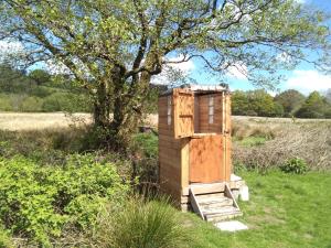 a wooden out house in a field with a tree at Serenity Lodge in Llandeilo