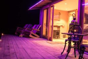 una camera con luci viola su un patio con sedie di Serenity Lodge a Llandeilo