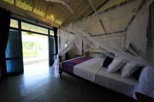 Yatiyantota的住宿－Leaf Olu Ella，一间卧室配有一张带天蓬的床
