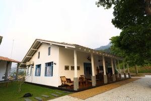 Una casa blanca con porche y sillas. en Leaf Olu Ella, en Yatiyantota