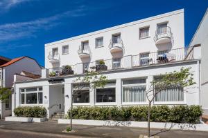 a white building with balconies on a street at Logierhaus am Rathaus in Norderney