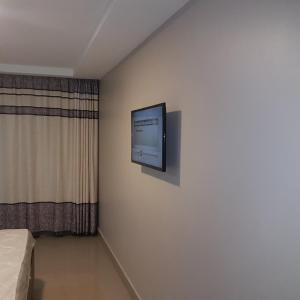 een televisie aan een muur in een kamer met een bed bij Adala Motel in Meru