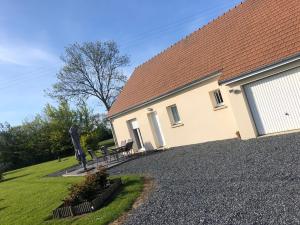 une maison avec un banc devant elle dans l'établissement pavillon individuel, à Cricqueville-en-Bessin