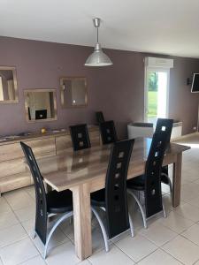 d'une table à manger entourée de chaises noires. dans l'établissement pavillon individuel, à Cricqueville-en-Bessin