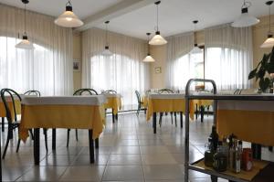 una sala da pranzo con tavoli, sedie e finestre di Hotel The Marquee a Castelnuovo di Garfagnana