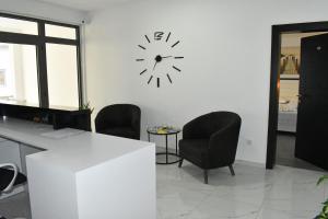 un ufficio con un orologio sul muro e sedie di Flo Apartments a Ulcinj