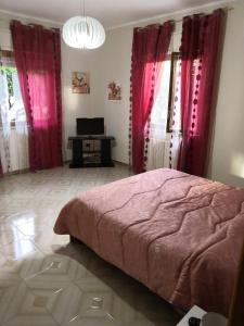 a bedroom with pink curtains and a bed and a desk at Case vacanze LE ROSE in Campofelice di Roccella