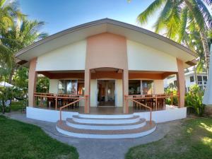 a building with a porch with stairs and palm trees at Kesa Cloud 9 Hotel & Resort Siargao in General Luna