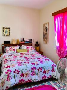 Pangiotas Pencione في كارباثوس: غرفة نوم مع سرير مع ستائر وردية ومروحة