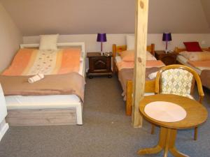 sypialnia z 2 łóżkami, stołem i krzesłem w obiekcie Pensjonat Dworek Baranówka w mieście Goniadz