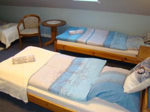 Pokój z 3 łóżkami, krzesłem i stołem w obiekcie Pensjonat Dworek Baranówka w mieście Goniadz