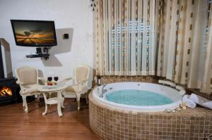 a large tub in a room with a tv and a fireplace at Renaissance Estate in Rosh Pinna