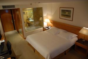 a bedroom with a large white bed and a bathroom at Eurobuilding Hotel & Suites Caracas in Caracas