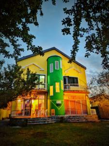 a large yellow and green house with a yard at Our Way Guest House & Hostel in Shkodër