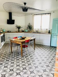 a kitchen with a table and chairs on a tiled floor at La Ferme de Maryse in Les Mesneux