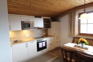 eine Küche mit weißen Schränken und einem Tisch mit Stühlen in der Unterkunft Pittlanderhof in Innsbruck