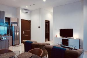 a living room with a flat screen tv and chairs at Lucky Tower Residence 2BR Top Floor Condo in Jakarta
