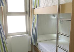 sypialnia z łóżkiem piętrowym i oknem w obiekcie Albergue Corredoiras w mieście Padrón