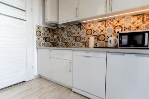 a kitchen with white cabinets and a tile wall at Pina House in Rewal