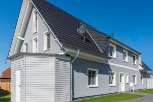 Casa blanca y azul con techo negro en Meerglas, en Zingst