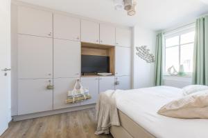 a white bedroom with a bed and a tv at Meerglas in Zingst