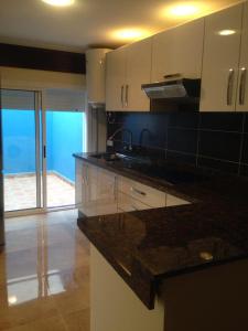 a kitchen with white cabinets and a black counter top at Oued Laou - Ground Floor in Oued Laou