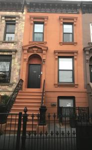 a orange building with stairs and a black door at Sandy's Place NYC 1 in Brooklyn