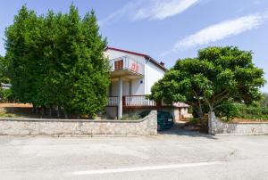 a house with a stone retaining wall and trees at Apartment Lordanic Zaglav, Dugi otok in Zaglav