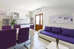 een woonkamer met een paarse bank en een keuken bij Apartment Lordanic Zaglav, Dugi otok in Zaglav