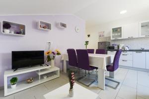 een woonkamer met een tafel en paarse stoelen bij Apartment Lordanic Zaglav, Dugi otok in Zaglav