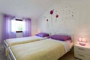 two beds in a bedroom with flowers on the wall at Apartment Lordanic Zaglav, Dugi otok in Zaglav