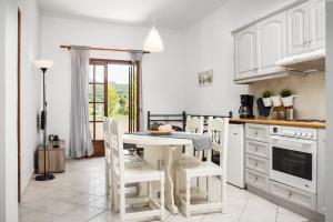 cocina con armarios blancos, mesa y sillas en Marias Seaside Apartments en Acharavi