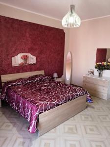 a bedroom with a bed and a red wall at Case vacanze LE ROSE in Campofelice di Roccella