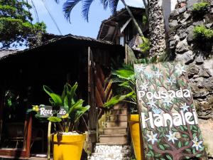 a sign in front of a house with plants at Pousada Hanalei in Itacaré