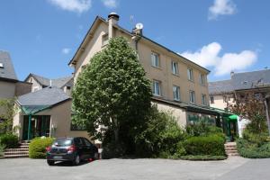 a car parked in front of a building with a tree at Logis Hôtel Restaurant Le Palous in Baraqueville