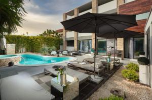 an outdoor patio with a pool and an umbrella at Boutique Hotel Chevalier - Adults Only in Medulin