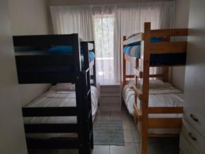 Habitación con 3 literas y ventana. en Unit 19 Villa Mia Apartment, en St Lucia