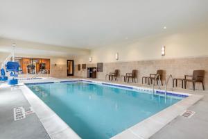 a large pool in a hotel with chairs and tables at Comfort Inn & Suites Schenectady - Scotia in Schenectady