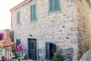 a large stone building with green shutters on it at Melpomeni Villa in Mythimna