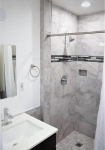 ein weißes Bad mit einer Dusche und einem Waschbecken in der Unterkunft Welcome Inn Motel in Montclair