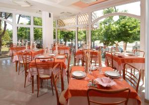 un ristorante con tavoli e sedie arancioni e finestre di Hotel Corallo a Misano Adriatico