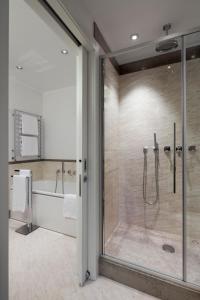 a bathroom with a tub and a shower with a glass door at Maison Milano | UNA Esperienze in Milan